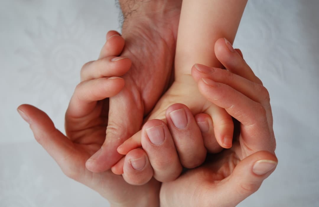 Les mains d'un adulte et celles d'un enfant enlacées